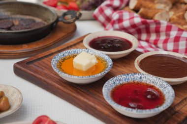 Çeşitli soslar ve ahşap bir tabakta sergilenen bir parça tereyağı..