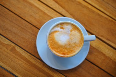 Kafedeki ahşap bir masanın üzerinde duran lezzetli bir fincan kahve..