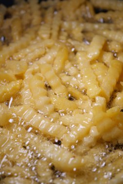 Altın sarısı, kırışık patates kızartması için sıcak yağda cızırdıyor..