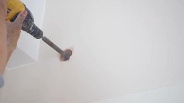 İşçi, kurulum için tavanda bir delik açmak için matkap kullanıyor.