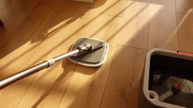 Doğal ışıkta paspas ve kova kullanarak ahşap yerleri paspaslıyorum..