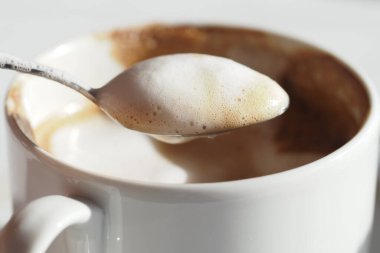 Bir kaşık, köpüklü kahveyle dolu bir fincanın üzerinde uçar..