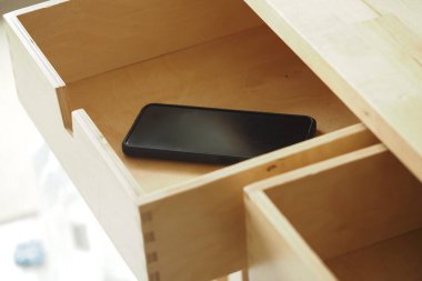 Akıllı telefon ahşap bir çekmecede minimalizmin altını çiziyor..