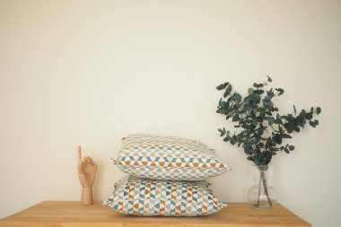 İki desenli yastık bir bitki düzeninin yanındaki ahşap bir masada dinleniyor..