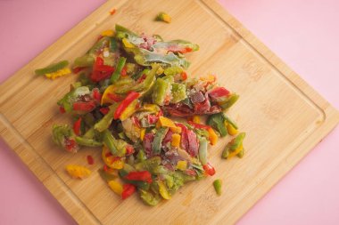 Doğranmış donmuş dolmalık biberler tahtada çeşitli renklerde sergilenir..