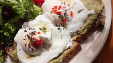 Avokado tostlu haşlanmış yumurta ve yeşillik içeren lezzetli bir yemeğin tadını çıkarın..