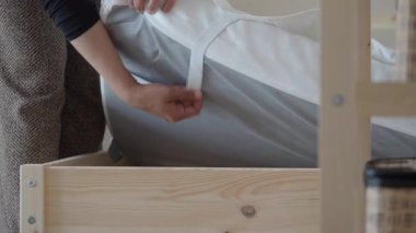 Bir insan sıcak bir alanda çarşafları değiştirerek yatak hazırlar..