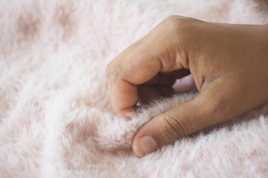 Bir el yumuşak pembe bir kumaşı okşar, rahat bir atmosfer yaratır..