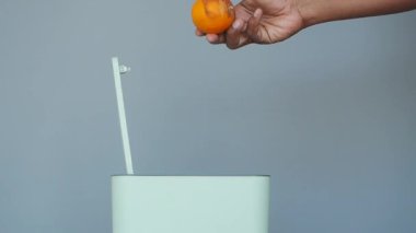 Bir insan, sürdürülebilirliği sağlamak için organik atıkları şık bir gübre kutusuna atar.