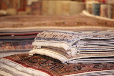 Canlı bir pazar ortamında düzgünce dizilmiş el yapımı halılar..