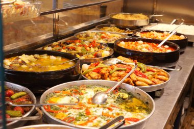 Bir markette metal tepsilerde çeşitli canlı yemekler sergileniyor..