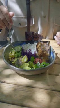 Taze sebze ve pirinçle besleyici bir yemeğin tadını çıkaran biri..