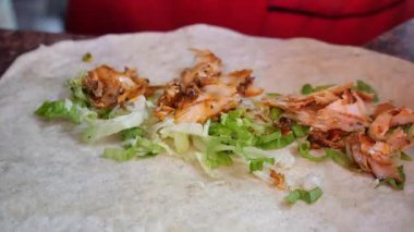 Şef ustaca ızgara tavuk ve marul ekliyor..