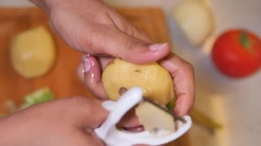 Eller mutfaktaki kesme tahtasına patates soyuyorlar..