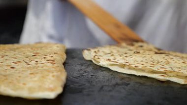 Becerikli ellerin mutfakta sıcak bir ızgarada ekmek yaptığını gör..