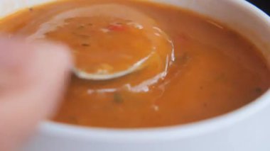 Lezzetli kremalı çorba, canlı renklerle beyaz bir kasede karıştırılıyor..