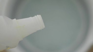 Birisi temizlik işleri için bir kova suya temizlik çözeltisi döker..