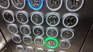 Kat tuşlarına basarken asansörle yukarı çıkmaya hazır olan yolcular.