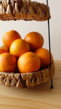 Örülmüş sepetteki parlak portakallar tazeliklerini ön plana çıkarıyor..