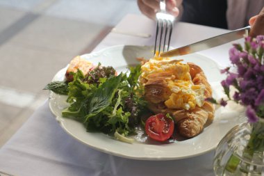 Kahvaltıda yumurta ve salata dolu lezzetli bir kruvasan yenir..