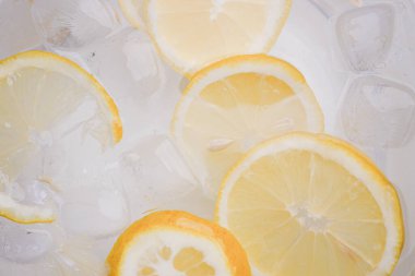 Limon dilimleri berrak suda buzda yüzer, ferahlatıcı bir görünüm yaratır..