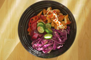 İçinde renkli sebzeler ve ızgara tavuk şeritleri olan taze salata kasesi..