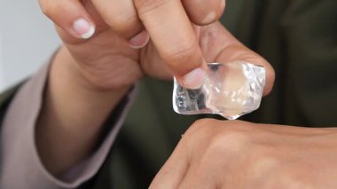 Kişi bileğindeki deri tahrişini azaltmak için buz küpü kullanır..