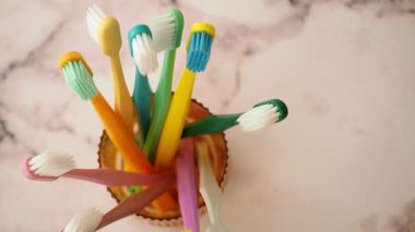 Parlak renkli diş fırçaları pürüzsüz bir yüzeyde bir kavanozda dinleniyor..