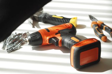 Bir kablosuz matkap yanında vidalar ve diğer araçlar ile bir tablo üzerinde durmaktadır.