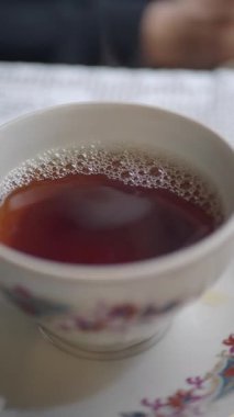 Sıcak bir fincan çay bir masada oturur, rahatlamaya ve rahatlamaya davet eder..