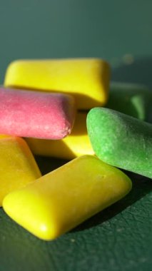 Colorful chewing gum on a green surface in bright light.