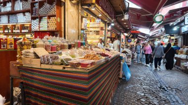 Müşteriler renkli baharat ve şekerlerle dolu kalabalık bir pazarı keşfediyorlar..