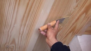 A skilled worker uses a putty knife to repair wood surface flaws indoors.