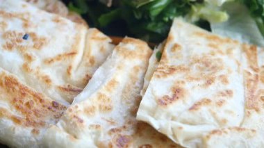 Flatbread is being served with fresh greens, highlighting its delicious taste.