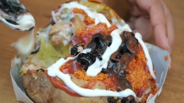 A delicious loaded baked potato topped with sauces and toppings is served.