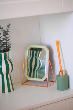 Stylish vases and a decorative mirror are arranged on a modern shelf.