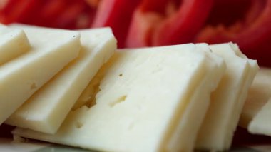 Fresh cheese and ripe tomatoes are being sliced for a healthy salad.