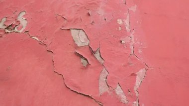 Close look at a worn pink wall with peeling paint and texture.