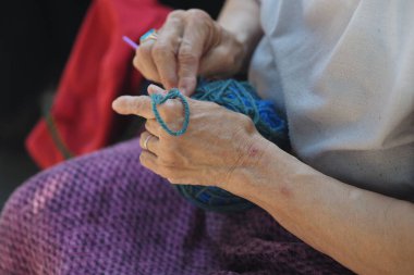 Yaşlı bir kadın ustaca örgü örer. Kucağında canlı bir iplikle..