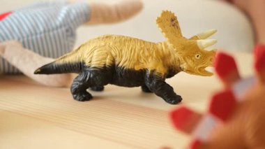 Renkli oyuncak dinozorlar rahat bir odada ahşap bir masada birlikte oynuyorlar..