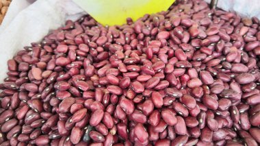Fresh red beans are spread out at a market stall during the day.