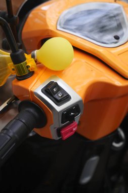 Close-up of motorcycle handlebar with controls and a playful balloon.