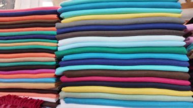 Yerel bir pazarda yığınlar halinde çeşitli renklerde canlı kumaşlar..