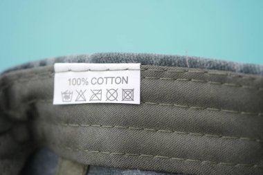 Giysi kumaşı üzerinde bakım talimatları olan bir pamuk etiketinin yakın görüntüsü.