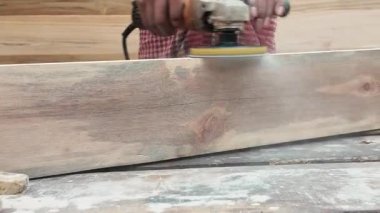 Zanaatkar parlak bir görünüm için ahşap bir kalas üzerinde zımpara kullanır..