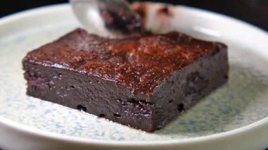 Zengin bir çikolatalı kek kesilir ve dekoratif bir tabakta servis edilir..