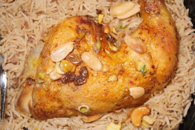 Bu yemek, kabarık pilav ve fındıklı yatakta servis edilen baharatlı tavuktan oluşuyor..