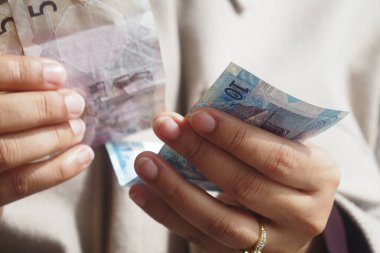 Bir insan markette alışveriş yaparken farklı banknotları sayar..