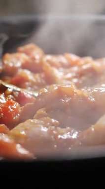 Karides bol domates soslu pişirir ve mutfakta buhar yükselir..