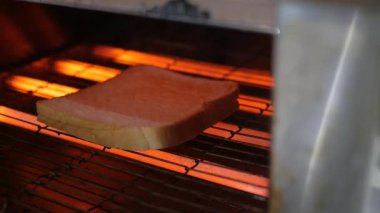 Bir dilim ekmek bir mutfak aletinin içinde kızartılıyor..